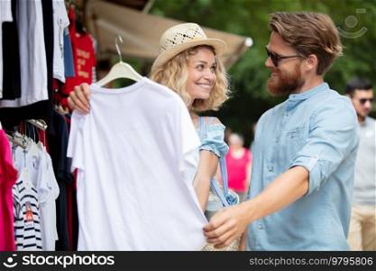 couple is buying a t-shirt outdoors