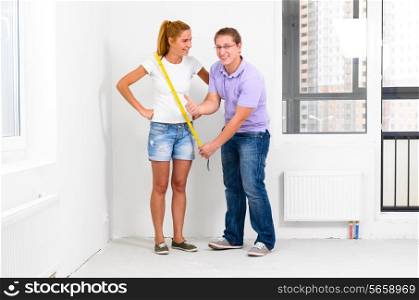 couple is measuring their new empty apartment