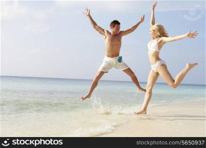 Couple Jumping In The Air On Tropical Beach