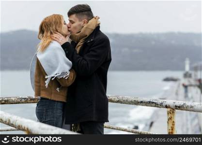 couple kissing by lake during winter