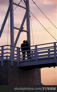 Couple kissing on pedestrian bridge at sunset in Perkins Cove, Maine