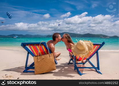 Couple kissing on tropical beach in loungers at Thailand