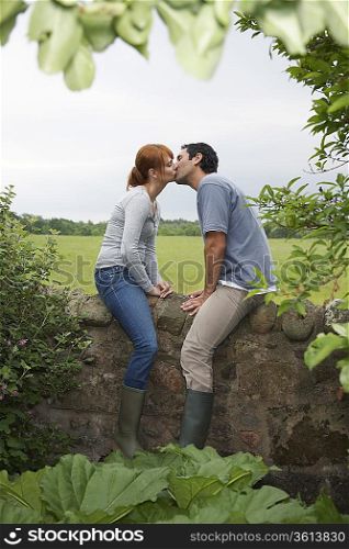 Couple kissing on wall in countryside
