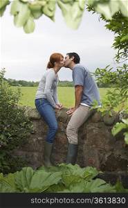 Couple kissing on wall in countryside