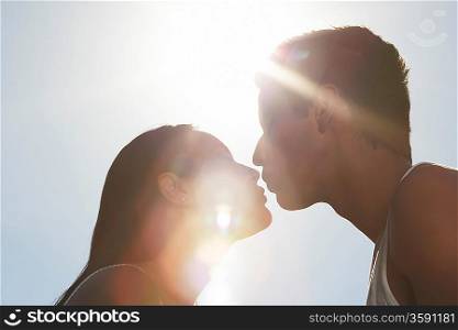 Couple kissing outdoors in sunlight profile