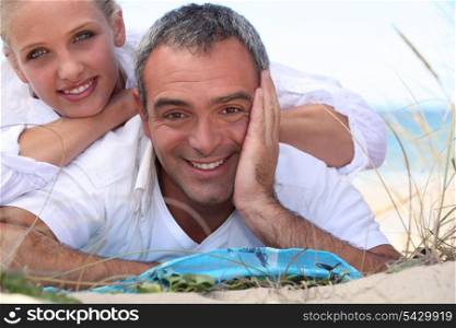 Couple laid on towel at the beach