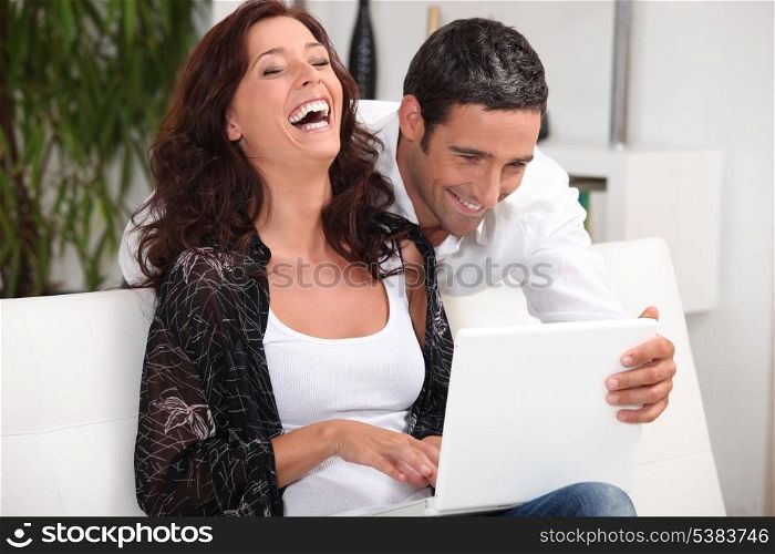 Couple laughing at their laptop