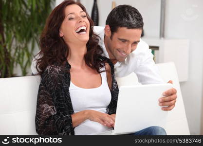 Couple laughing at their laptop