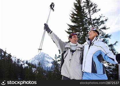Couple laughing standing on ski slope low angle view