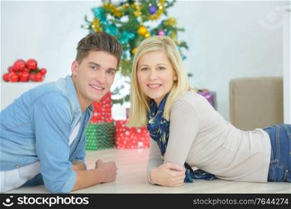 Couple layed in front of Christmas tree
