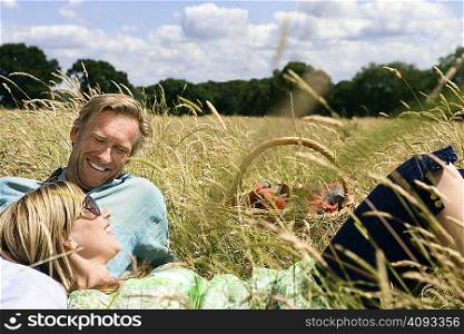 Couple laying field, with picnic basket