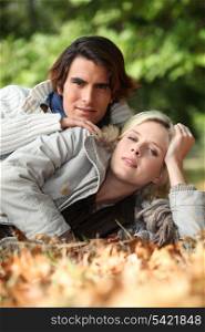 Couple laying in autumnal leaves