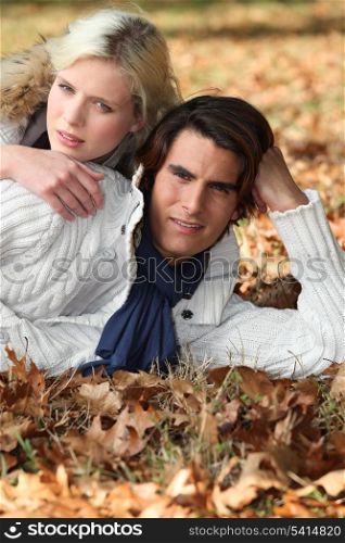 Couple laying in fallen leaves