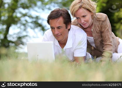 Couple laying in the park with laptop