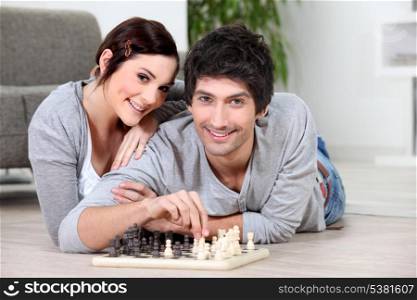 Couple laying on floor playing chess