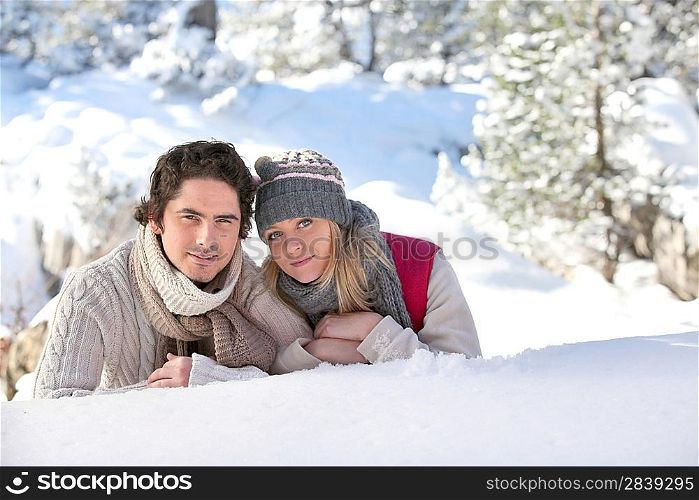 Couple laying on snowy hillside