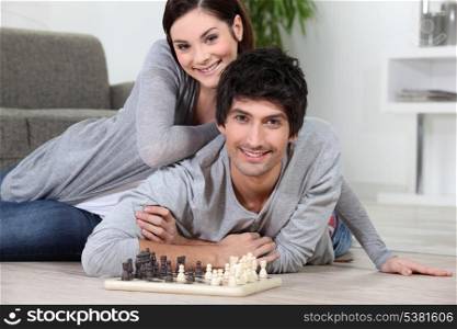Couple laying on the floor playing chess