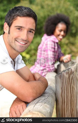 couple leaning against a wooden barrier