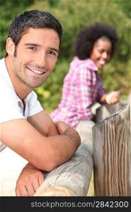 couple leaning against a wooden barrier