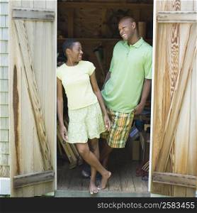 Couple leaning against a wooden door and smiling