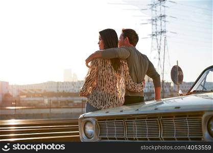 Couple leaning against car bonnet looking away, Los Angeles, California, USA