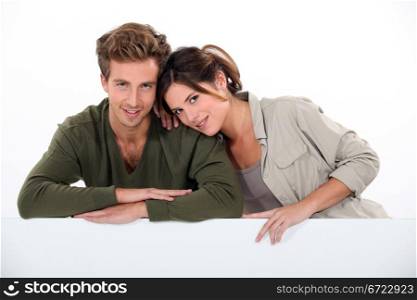 Couple leaning on blank poster