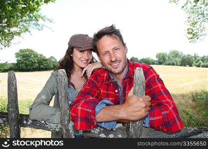 Couple leaning on fence in country field