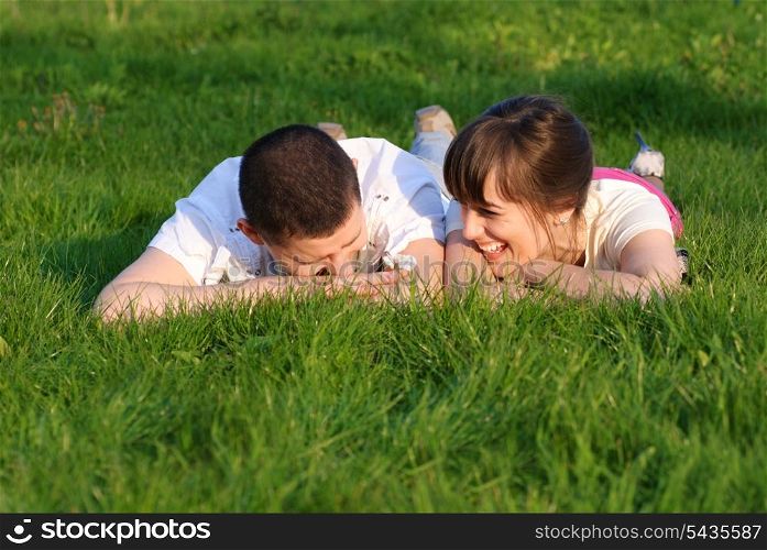 Couple lie on the grass and look up. Shallow DOF. Outdoor portrait