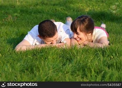 Couple lie on the grass and look up. Shallow DOF. Outdoor portrait