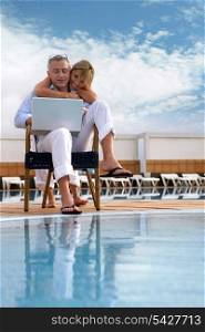 Couple looking at a laptop by a pool