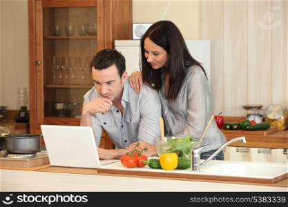 Couple looking at a laptop in their kitchen