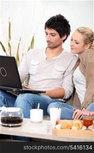 Couple looking at a laptop over breakfast