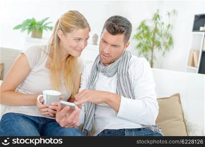 Couple looking at a smarphone on the sofa