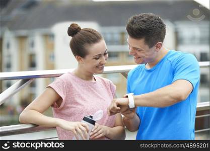 Couple Looking At Activity Tracker Whilst Exercising In City