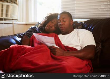Couple Looking At Bills Keeping Warm Under Blanket At Home