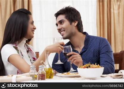 Couple looking at each other while clinking wine glass at restaurant