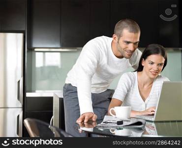 Couple looking at lap top in modern kitchen