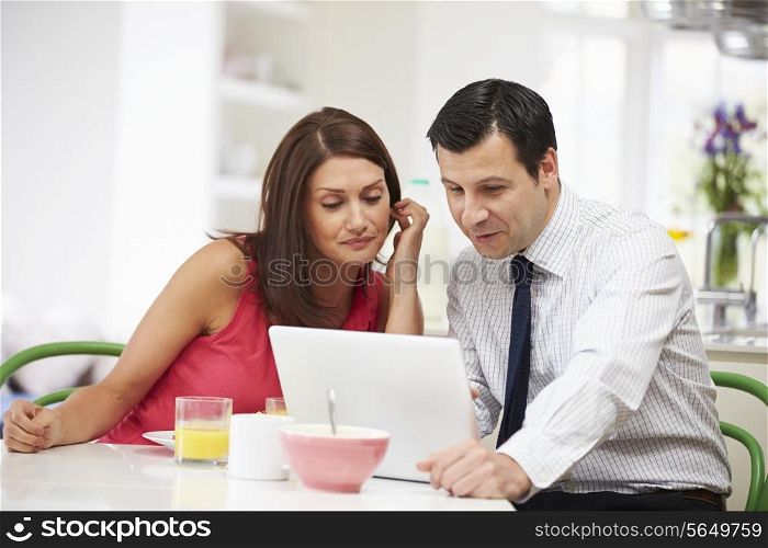 Couple Looking at Laptop Over Breakfast