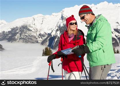 Couple Looking At Map Whilst On Ski Holiday In Mountains