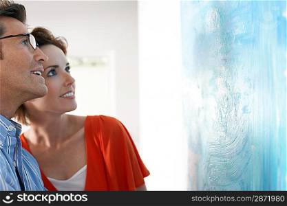 Couple looking at modern art painting in gallery