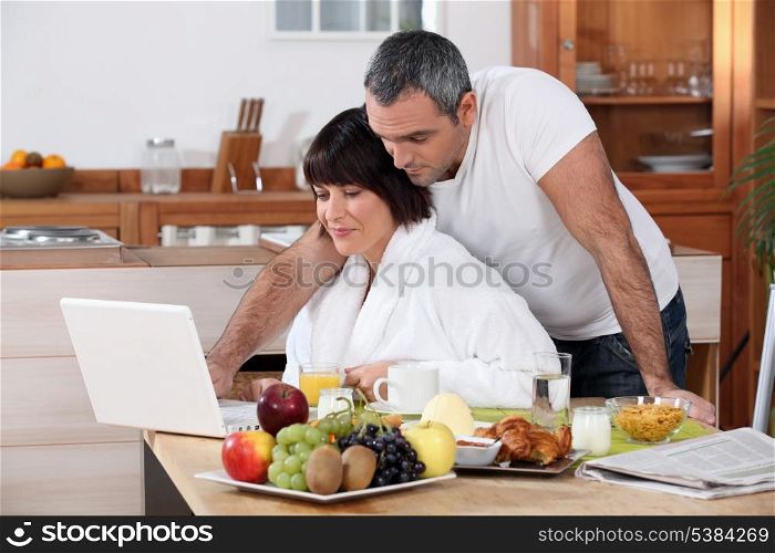 Couple looking at their laptop during breakfast