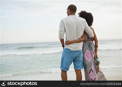 Couple looking out to sea from beach, Rio De Janeiro, Brazil