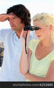 Couple looking through binoculars whilst on vacation
