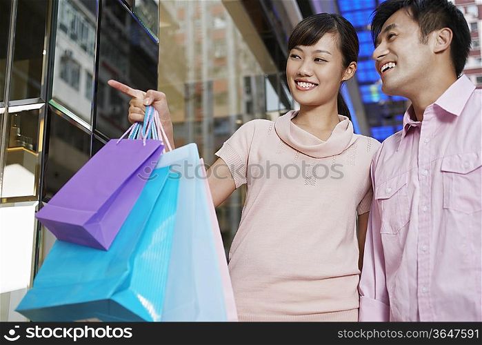 Couple looking through shop window at display