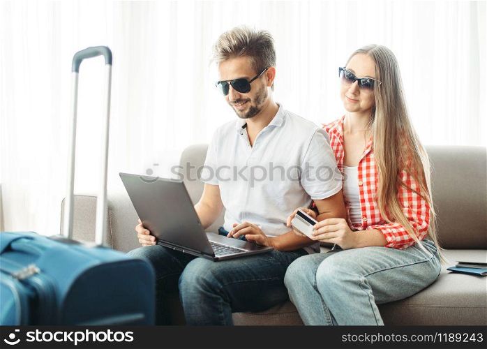 Couple looks on laptop screen, fees on journey concept. Luggage preparation. Travelling or tourism. Couple looks on laptop screen, fees on journey