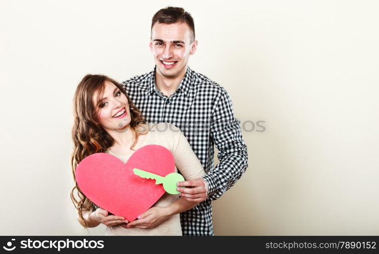 Couple love and happiness concept. Smiling young man and woman holding big red heart with key