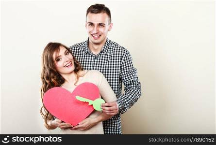 Couple love and happiness concept. Smiling young man and woman holding big red heart with key