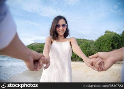 Couple lover hold hands together on tropical summer beach. Focus on girlfriend smiling to boyfriend with happiness activity. Romantic love travel togetherness. Summer vacation lover lifestyle concept.