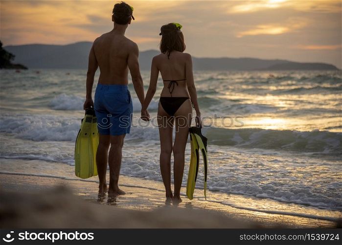 Couple lover holding hands together on the beach during sunset on honeymoon trip at tropical summer island. Honeymoon adventure trip for young couple traveler.