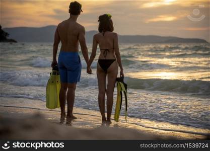 Couple lover holding hands together on the beach during sunset on honeymoon trip at tropical summer island. Honeymoon adventure trip for young couple traveler.